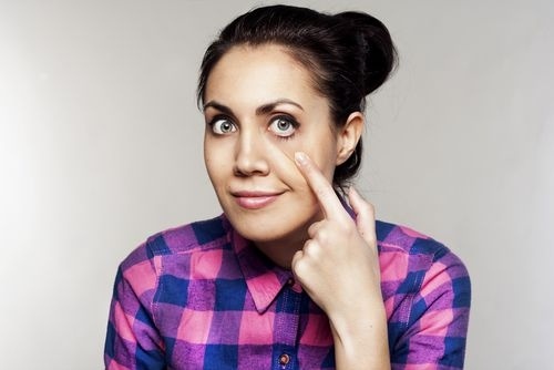 Vytírá si řasenku z vnitřního koutku oka a pak to zkontroluje.